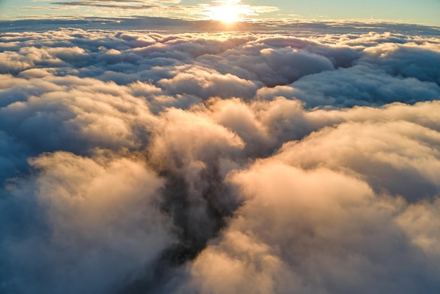 Luchtfoto van bovenaf op grote hoogte van dichte gezwollen cumuluswolken die 's avonds vliegen Geweldige zonsondergang vanuit het oogpunt van het vliegtuigraam