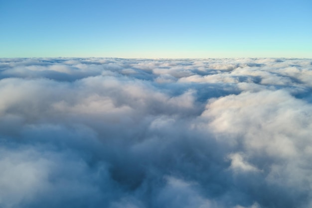 Luchtfoto van bovenaf op grote hoogte van dichte gezwollen cumuluswolken die 's avonds vliegen Geweldige zonsondergang vanuit het oogpunt van het vliegtuigraam