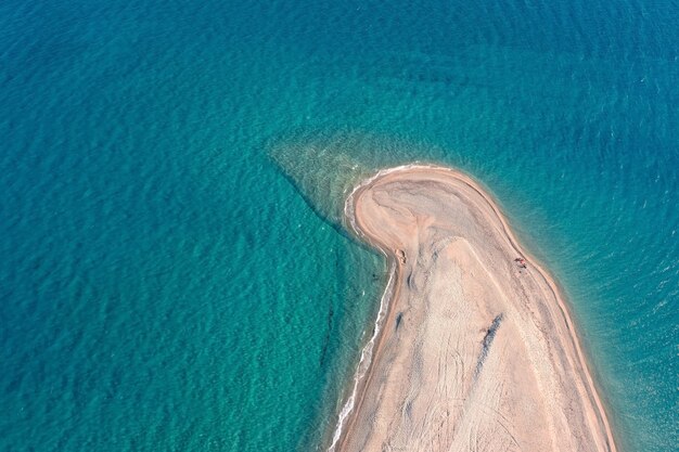 Luchtfoto van bovenaf van een lang smal zandstrand dat zich uitstrekt tot in de turquoise zee