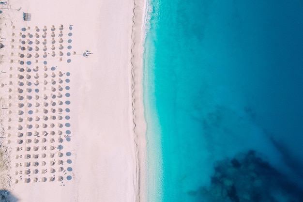 Luchtfoto van bovenaf van een schoon strand uitgerust met parasols en ligbedden op de turquoise zee. griekenland.