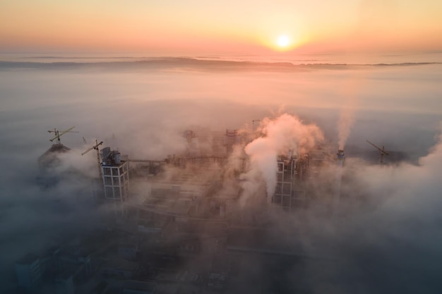 Luchtfoto van cementfabriek met hoge betonfabrieksstructuur en torenkraan op industriële productielocatie op mistige ochtend Vervaardiging en wereldwijd industrieconcept
