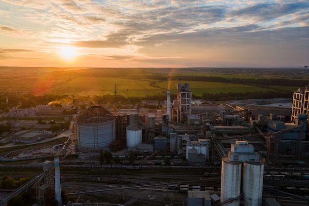 Luchtfoto van cementfabriek met hoge betonnen fabrieksstructuur en torenkraan op industrieel productiegebied. Vervaardiging en wereldwijd industrieconcept.