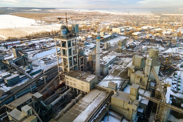 Luchtfoto van cementfabriek met hoge fabrieksstructuur en torenkraan op industrieel productiegebied bij zonsondergang