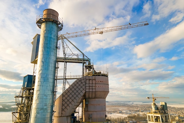 Luchtfoto van cementfabriek met hoge fabrieksstructuur en torenkraan op industrieel productiegebied.