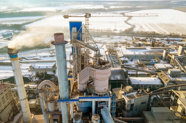 Luchtfoto van cementfabriek met hoge fabrieksstructuur en torenkraan op industrieel productiegebied.