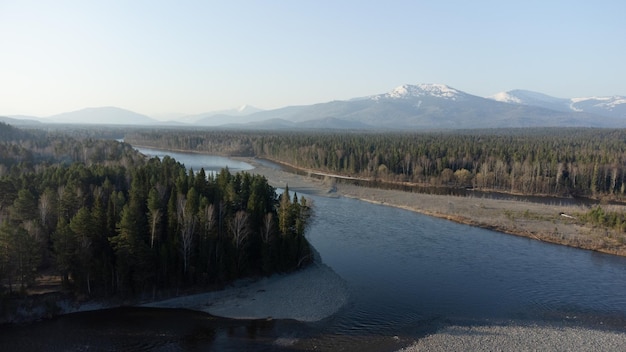 Luchtfoto van de bergrivier in het taigabos in het vroege voorjaar in zonsondergangtijd Siberisch of Canadees landschap van bovenaf