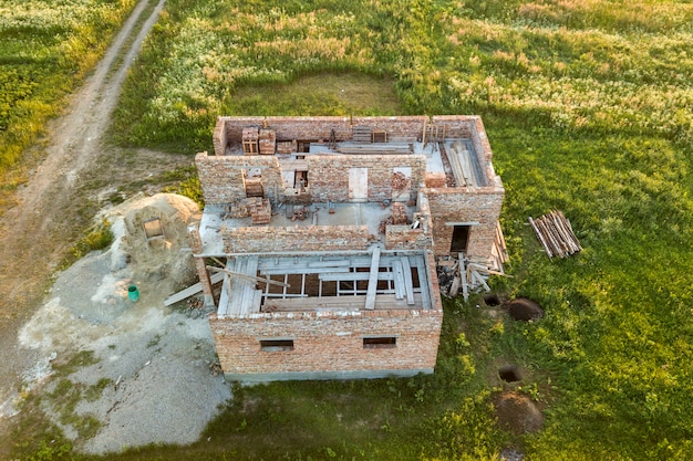 Foto luchtfoto van de bouwplaats voor toekomstige huis, bakstenen kelderverdieping en stapels bakstenen.