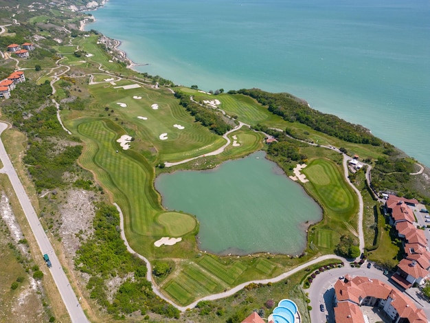 Luchtfoto van de golfbaan strekt zich uit onder de weelderige groene fairways die het adembenemende kustpanorama aanvullen