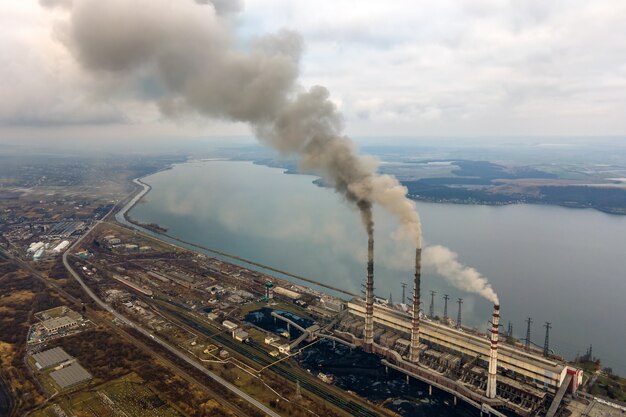 Luchtfoto van de hoge pijpen van de kolencentrale met zwarte rook die de vervuilende atmosfeer omhoog beweegt.