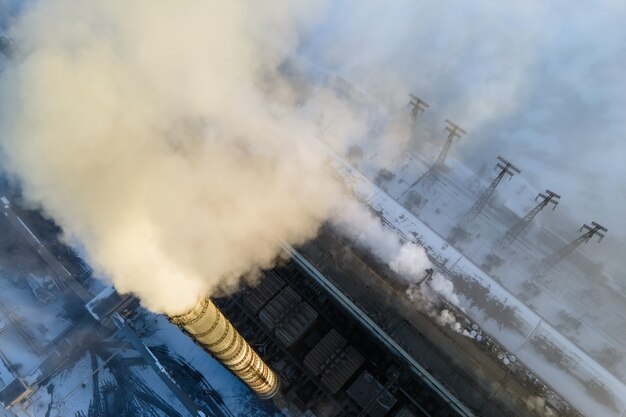 Luchtfoto van de hoge pijpen van de kolencentrale met zwarte rook die de vervuilende atmosfeer omhoog beweegt.