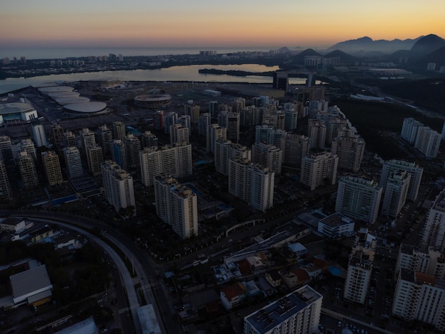 Luchtfoto van de lagune van jacarepagua in rio de janeiro brazilië residentiële gebouwen en bergen rond het meer barra da tijuca strand op de achtergrond zonnige dag zonsondergang drone foto