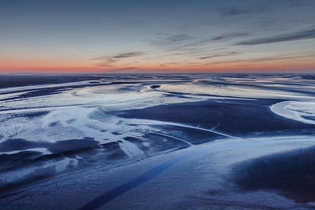 Luchtfoto van de oceaan bij eb na zonsondergang vanaf het klooster van Mont Saint Michel.