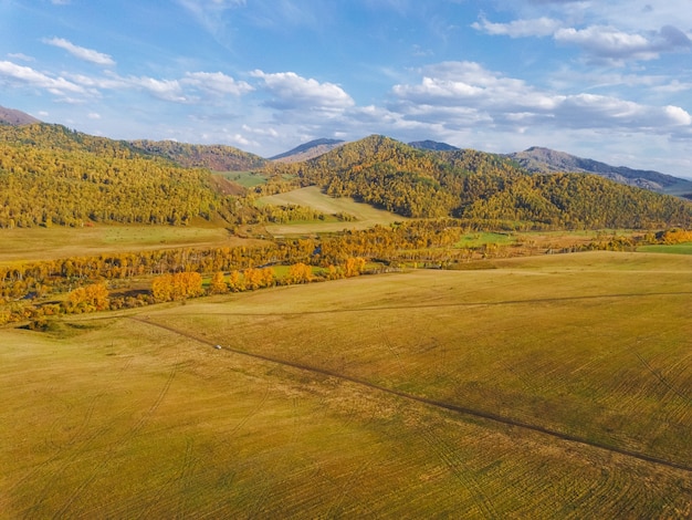 Luchtfoto van de pittoreske herfstbergen met velden met geoogste en wintergewassen. Heldere herfstkleuren,