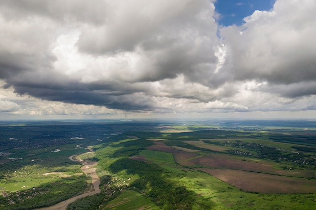 Luchtfoto van de stad of dorp met rijen van gebouwen en bochtige straten tussen groene velden in de zomer. platteland landschap van bovenaf.