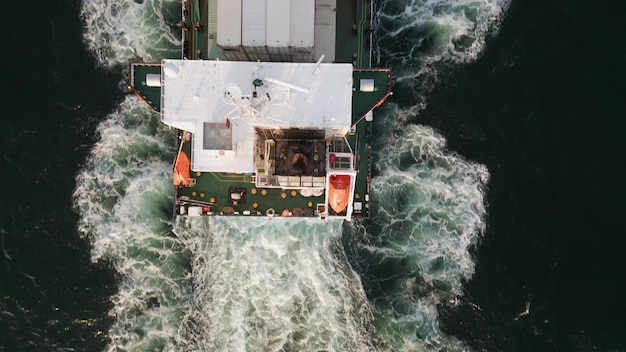 Luchtfoto van een containerschip dat op zee vaart, de enorme romp die door het water snijdt terwijl het vracht over de wereld vervoert Het schip wordt omringd door eindeloze golven