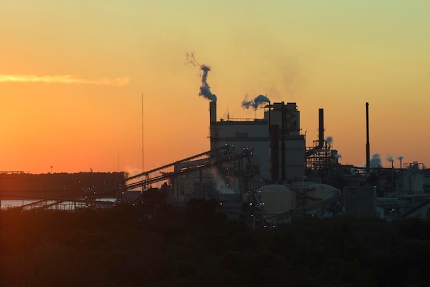 Luchtfoto van een grote fabriek met een schoorsteen van de vervuilende atmosfeer van het productieproces op de fabriekswerf Industrieel terrein bij zonsondergang