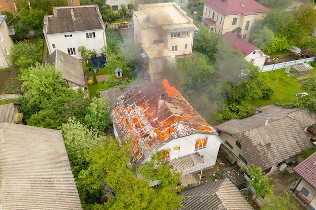 Luchtfoto van een huis in brand met oranje vlammen en witte dikke rook