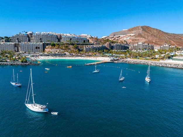 Luchtfoto van een jacht in de diepblauwe zee aan de kustlijn van Gran Canaria