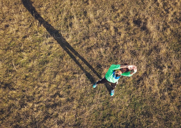 Luchtfoto van een jonge fitnessvrouw die rekoefeningen doet na het joggen in de natuur.