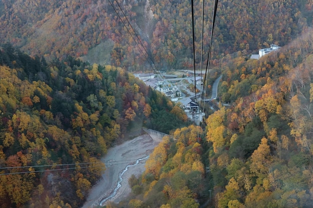 Luchtfoto van een kabelbaan van Kurodake Ropeway vliegen over kleurrijke herfstbossen