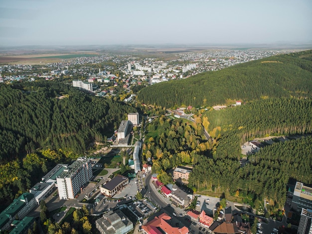 Luchtfoto van een klein stadje in het Altai-gebied Bovenaanzicht van de badplaats Belokurikha Vogelperspectief van de huizen tussen de bossen op de hellingen van de bergen