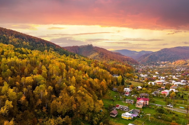 Luchtfoto van een landelijk dorp met kleine huizen tussen herfstbergheuvels