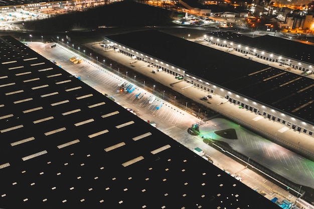 Luchtfoto van een magazijn met goederen 's nachts luchtfoto van het logistiek centrum felverlichte aanhangwagens en vrachtwagens op de parkeerplaats van een magazijn