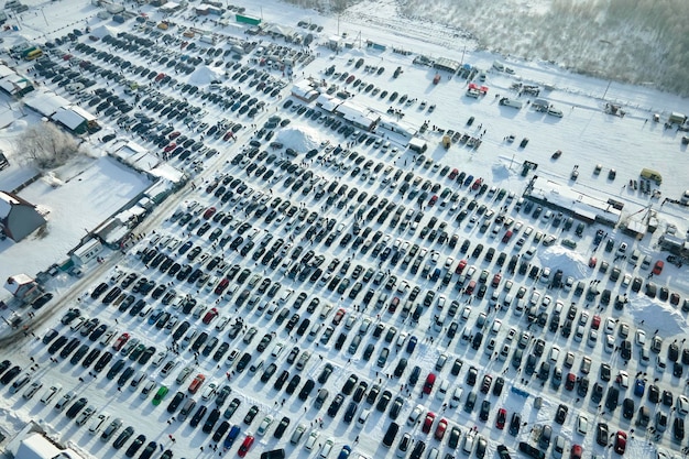 Luchtfoto van een open marktterrein voor voertuigen met veel geparkeerde auto's en klanten die in de winter lopen