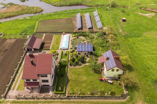 Luchtfoto van een privéwoning in de zomer met blauwe fotovoltaïsche zonnepanelen op het dak en in de tuin.