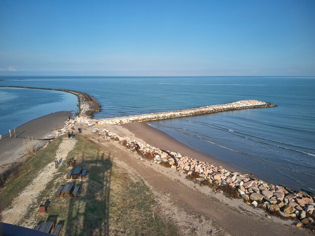 Luchtfoto van een systeem van dammen van kiezelstenen gecreëerd om het strand van Rosolina in Italië te beschermen; een voorbeeld van hoe natuurlijk en kunstmatig naast elkaar bestaan bij het creëren van een uniek landschap.