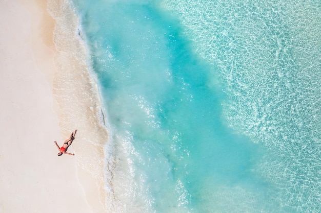 Luchtfoto van een vrouw op het strand in een bikini die ligt en zonnebaadt. Ontspanning vrije tijd schilderachtig