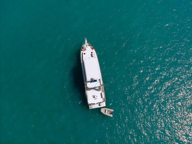 Luchtfoto van een witte boot met een scherpe boeg en een kleine boot ernaast die over de zee vaart