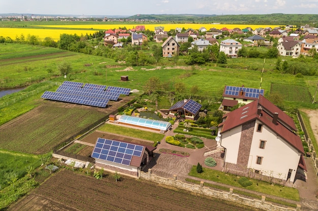 Luchtfoto van een woonhuis in de zomer met blauwe zonne-fotovoltaïsche panelen op het dak en in de tuin.