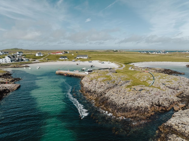 Luchtfoto van een zandstrand langs het eiland Tiree in Schotland met huizen en een turquoise zee-lagune