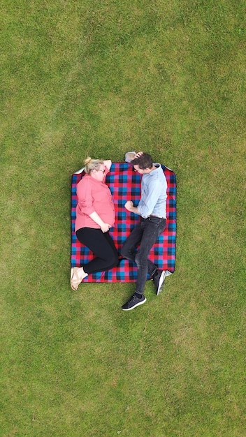 Luchtfoto van een zwangere vrouw en partner ontspannen in een park
