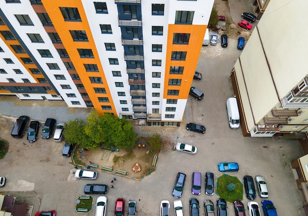 Luchtfoto van geparkeerde auto's op parkeerplaats tussen hoge flatgebouwen.