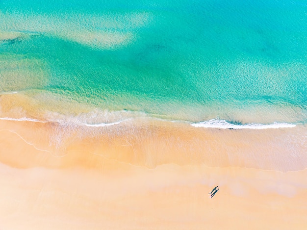 Luchtfoto van geweldig strand met huwelijksreis paar wandelen op strand in ochtendlicht dicht bij turquoise zee bovenaanzicht van zomer strand landschapvakantie reizen en tour concept