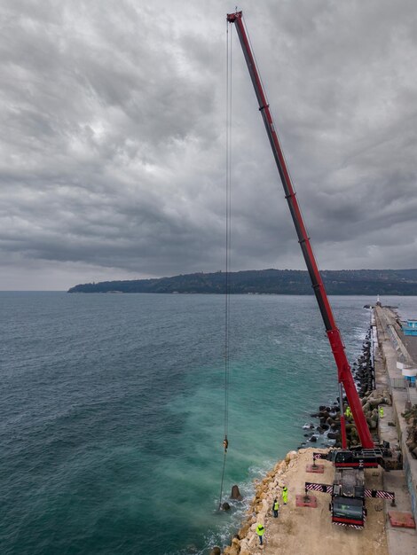 Luchtfoto van golfbrekerconstructie Bulldozer en kraan op een stapel rotsblokken in de zee