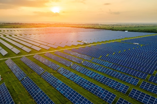 Luchtfoto van grote duurzame elektrische centrale met veel rijen fotovoltaïsche zonnepanelen voor het produceren van schone elektrische energie in de avond. Hernieuwbare elektriciteit met nul-emissieconcept.