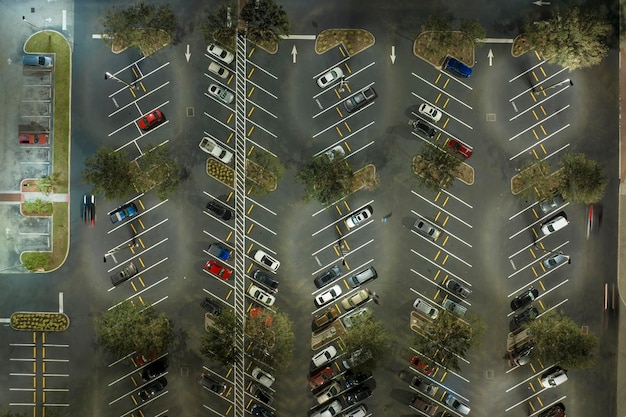 Luchtfoto van grote parkeerplaats 's nachts met veel geparkeerde auto's Donker parkeerterrein bij supercenter winkelcentrum met lijnen en markeringen voor voertuigplaatsen en richtingen