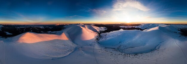 Luchtfoto van het adembenemende winterpanorama van de besneeuwde hellingen en heuvels tussen de weelderige witte wolken Het concept van betoverende harde winternatuur