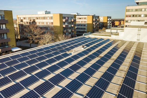 Luchtfoto van het blauwe glanzende systeem van fotovoltaïsche panelen op commercieel dak dat hernieuwbare schone energie produceert.