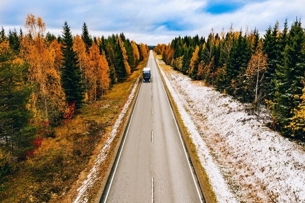 Luchtfoto van het eerste bos van de sneeuwherfstkleur en een weg met auto in Finland Lapland