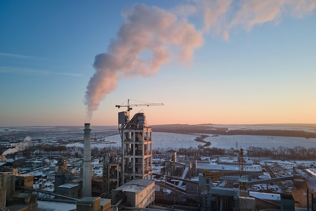Luchtfoto van het productiegebied van de cementfabriek met hoge betonnen fabrieksstructuur en torenkranen op industrieterrein Broeikasgasrook vervuilende lucht Vervaardiging en wereldwijd industrieconcept