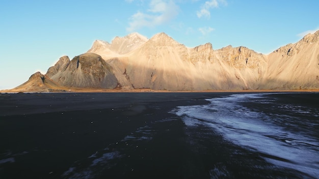 Luchtfoto van het Vestrahorn-gebergte in IJsland, het strand van Stokksnes en het schiereiland dat een prachtig Scandinavisch landschap vormt. Spectaculair landschap met zwart zandstrand, IJslandse natuur. Slow motion.