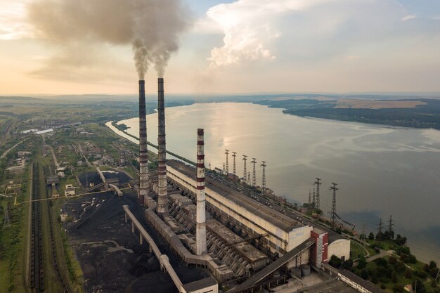 Luchtfoto van hoge schoorsteenpijpen met grijze rook van kolencentrale. productie van elektriciteit met fossiele brandstof.