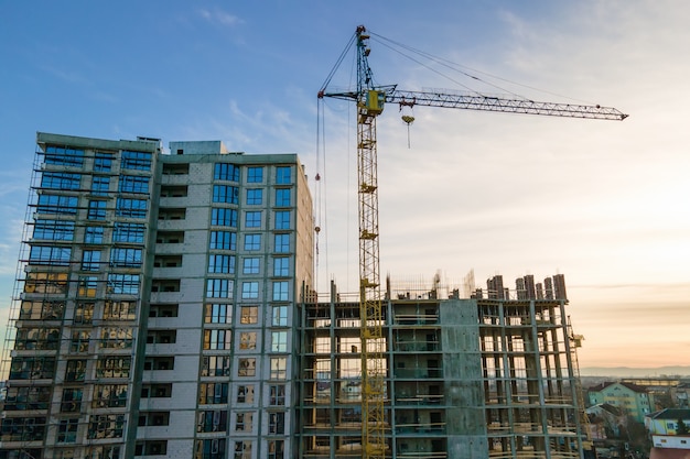 Luchtfoto van hoge torenkraan en residentieel appartementengebouw in aanbouw bij zonsondergang. Vastgoed Ontwikkeling.