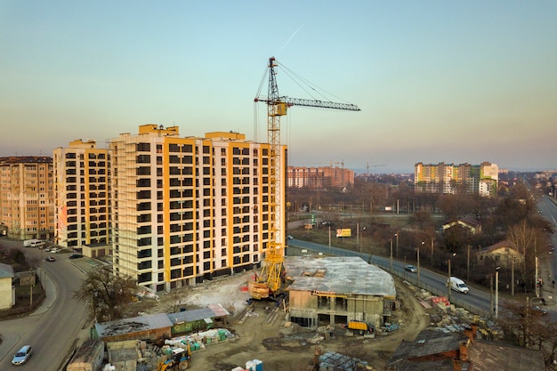 Luchtfoto van hoog appartementencomplex complex, onvoltooide gebouw met steigers en toren kraan op blauwe hemel kopie ruimte. Drone fotografie.