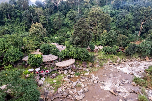 Luchtfoto van houten bungalow in tropisch regenwoud met natuurlijke stroomversnellingen in de vallei in nationaal park