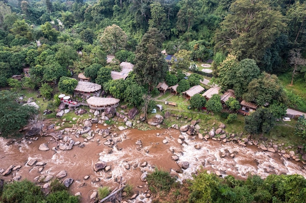 Luchtfoto van houten bungalow in tropisch regenwoud met natuurlijke stroomversnellingen in de vallei in nationaal park